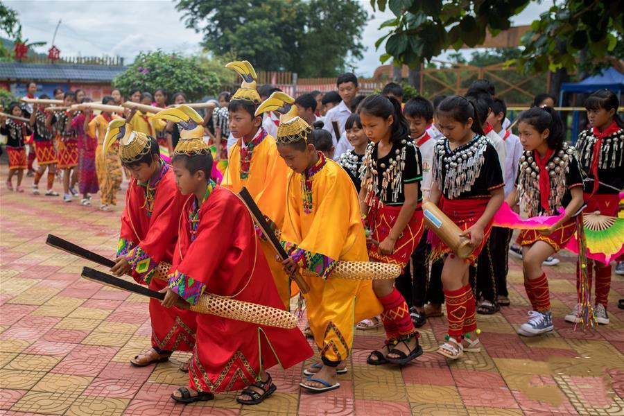 Boys dressing colorful gowns and hornbill-shaped headwear lead the dance