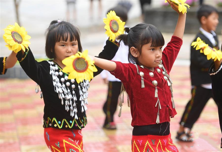 Jingpo girls dance with flowers in their hands