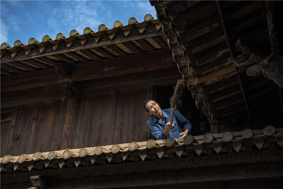 Yang Guobao, a local resident from Shiping cleans up his upturned roof with care