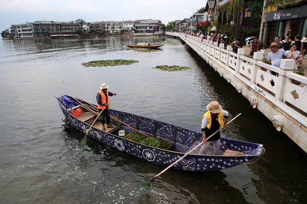 Environmental protection staff in Shuanglang town remove debris from the lake