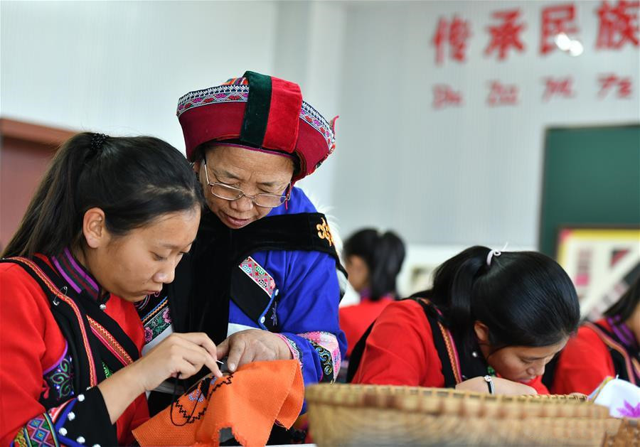 National intangible cultural heritage inheritor Bi Yueying guides a student in Shilin County of Kunming, Yunnan