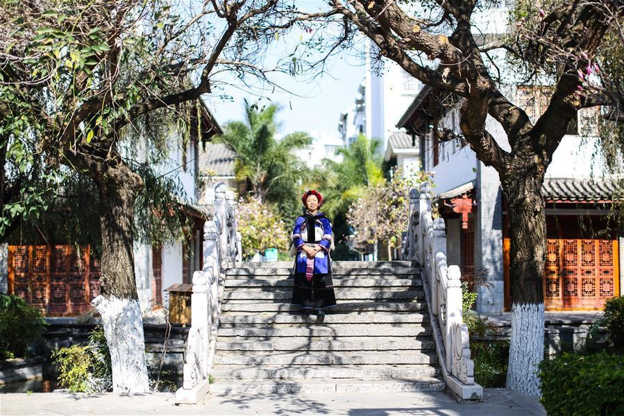 National intangible cultural heritage inheritor Bi Yueying stands on a stone bridge in Shilin County of Kunming, Yunnan