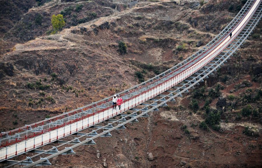 People walk on a bridge spanning the Niulan River in southwest China on Dec. 11, 2019